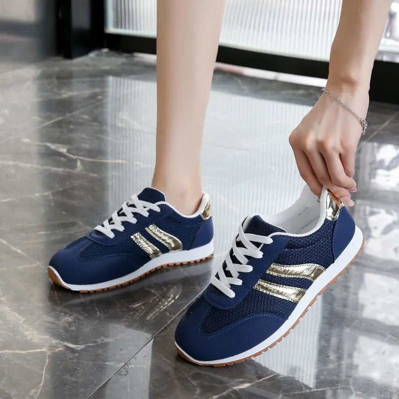 Blue women's casual tennis shoes with a cross shoulder strap and flat rubber sole on a white background.