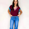 Burgundy v neck short sleeve sweater with contrast trim and loose fit on a woman