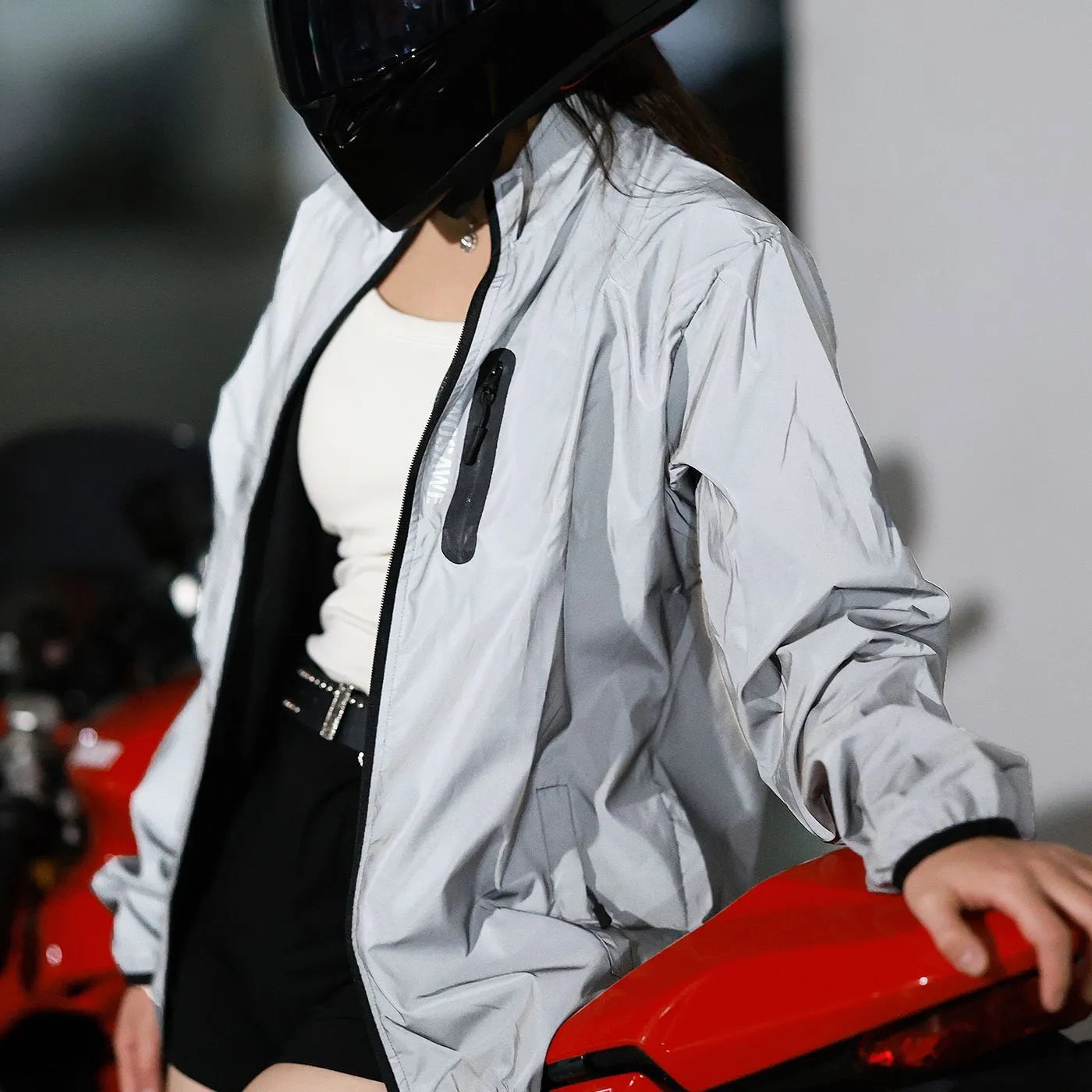 Silver waterproof polyester long sleeved work top laid flat, showing long sleeves and front zip.