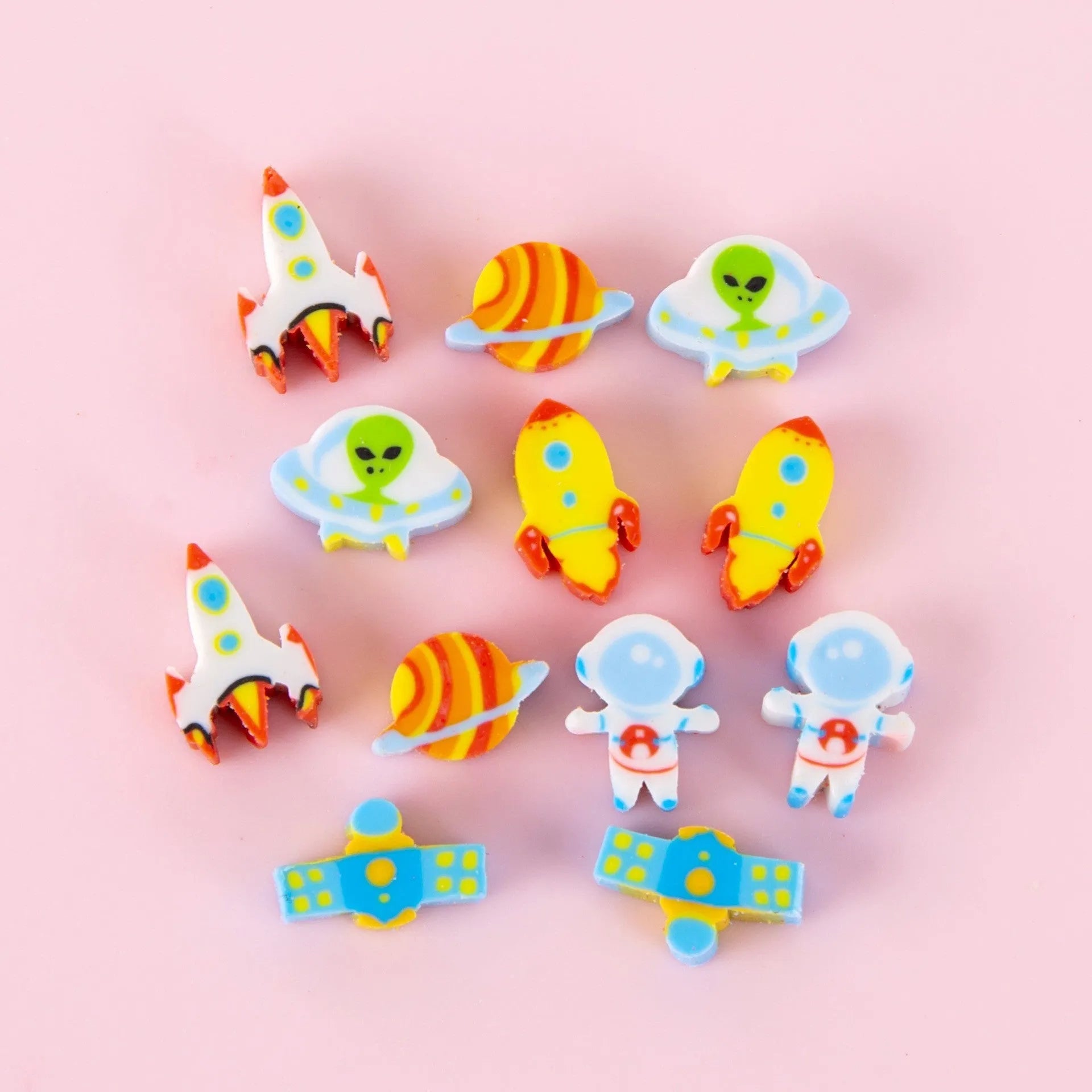 Open pearlescent film bag showing 50 small colourful cartoon fruit-themed rubber erasers.