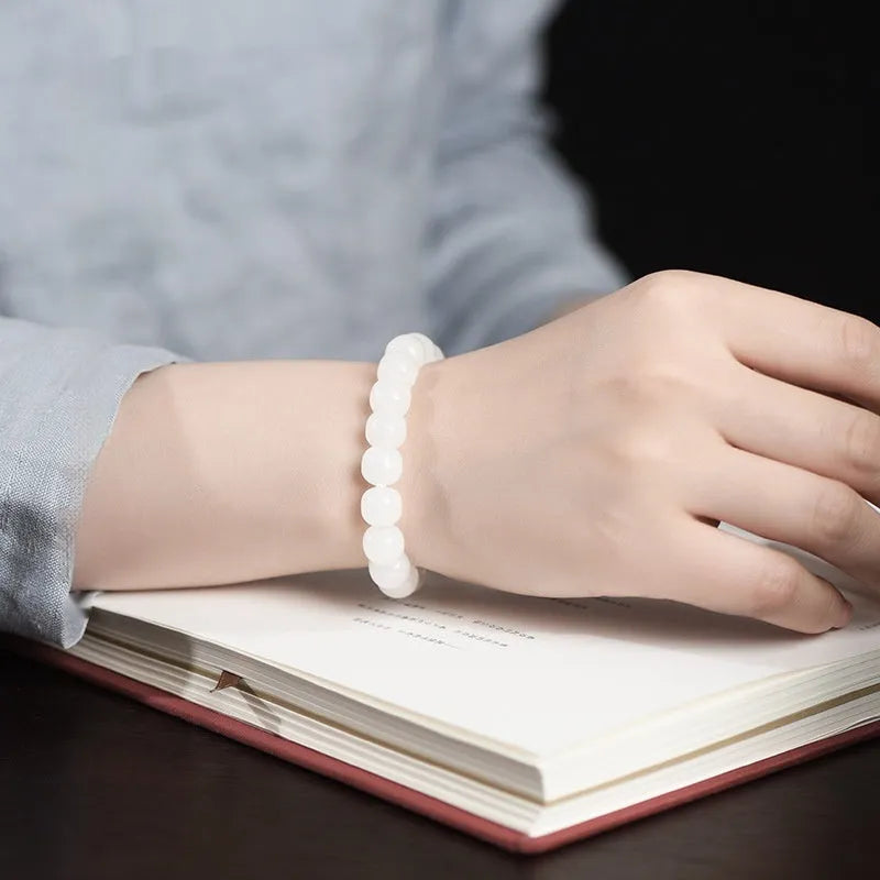 White Hetian jade barrel bead bracelet on a wrist, showing the traditional bead design.