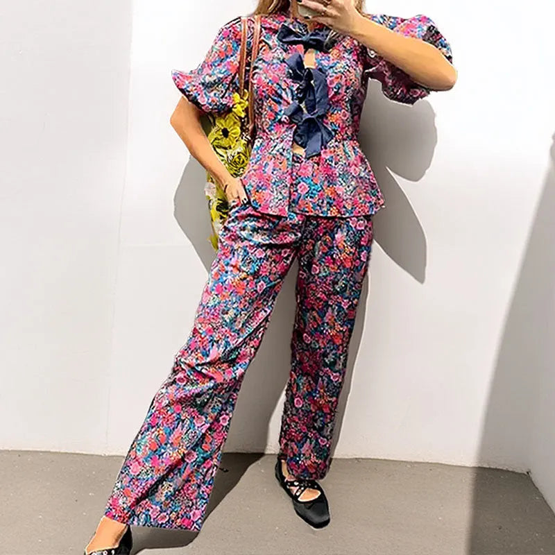 Women's floral print trousers suit with tie-neck blouse featuring puff sleeves and matching long trousers