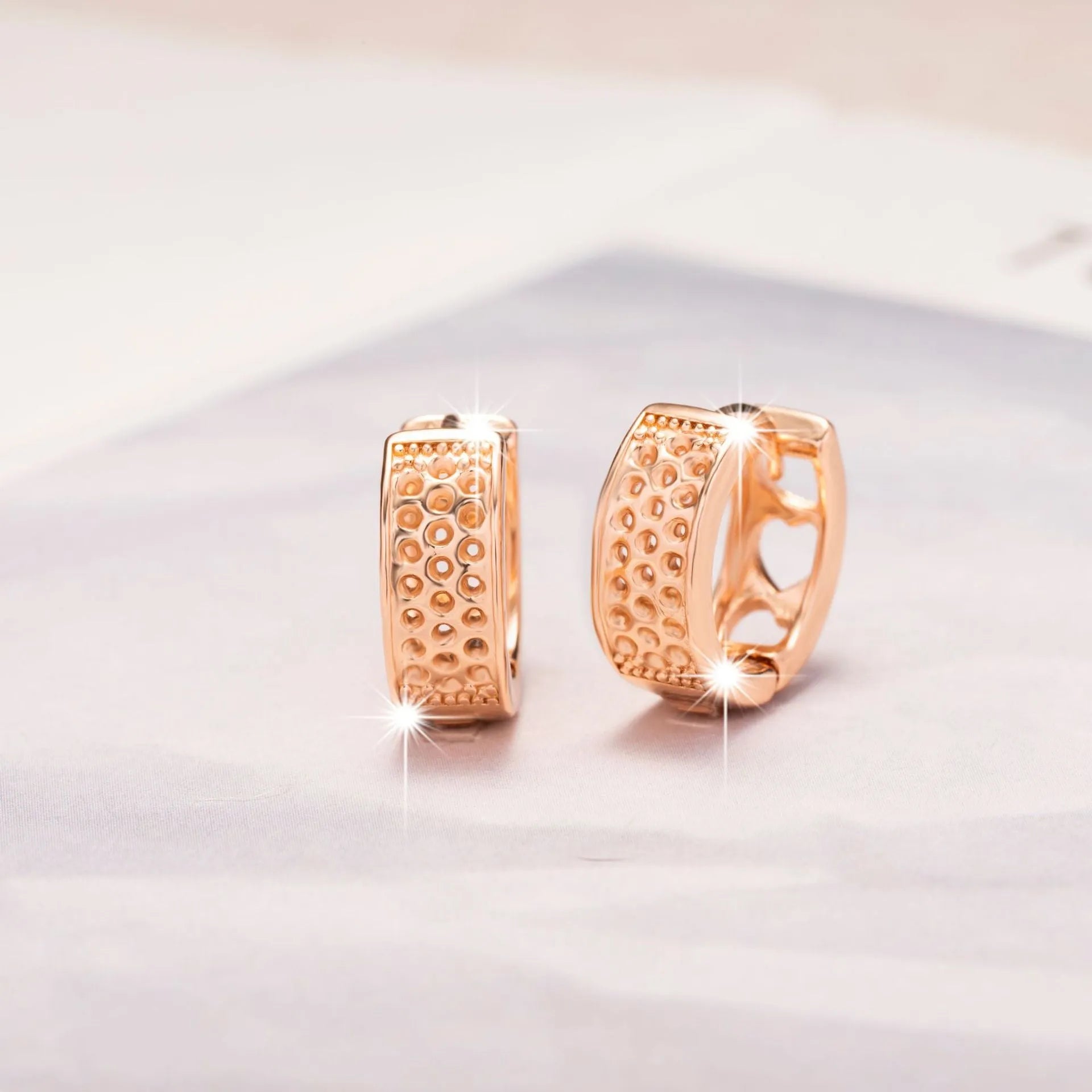 Rose gold electroplated earrings with hollow three-heart design in circular shape
