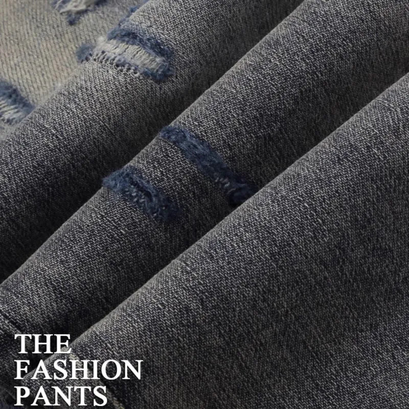 Men's slim fit jeans in old colour with distressed holes and embroidered patches on the legs.