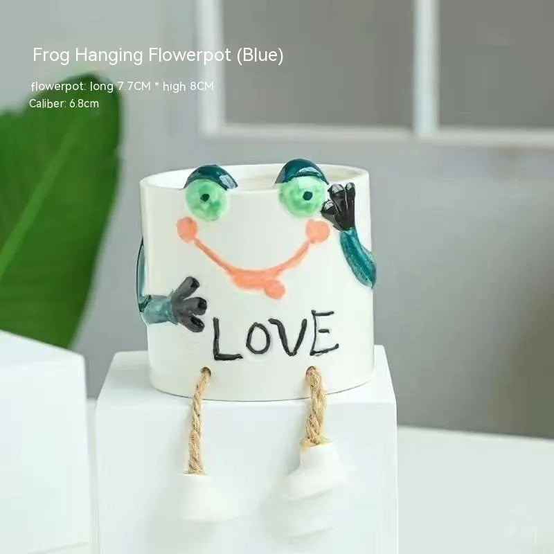 Ceramic cartoon-style hanging foot flowerpot for succulent plants on a desktop.