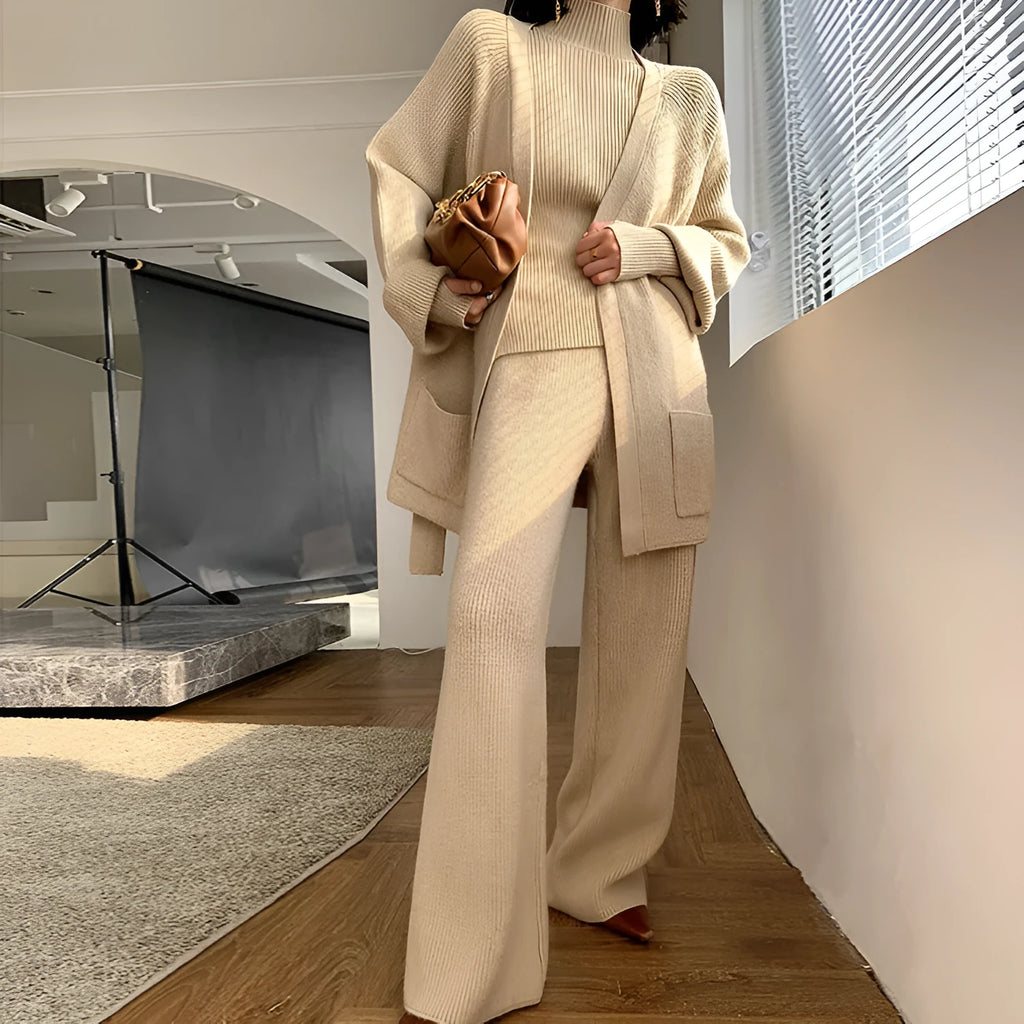 Women's knitted three-piece set showing top, wide-leg trousers, and cardigan in solid colour with leather stitching details