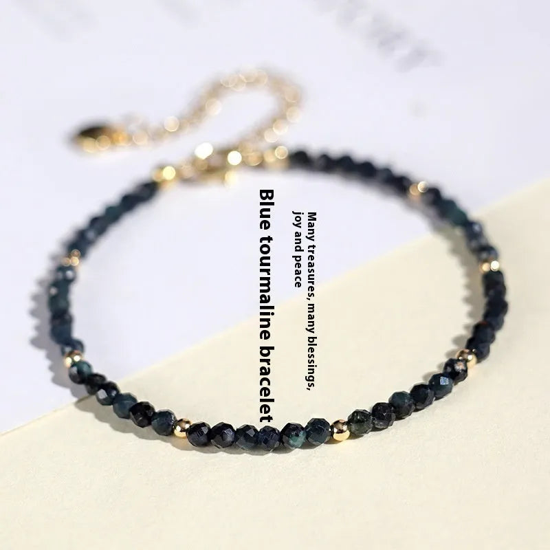 Close-up of a blue tourmaline beaded bracelet with metallic spacer beads on a woman's wrist.