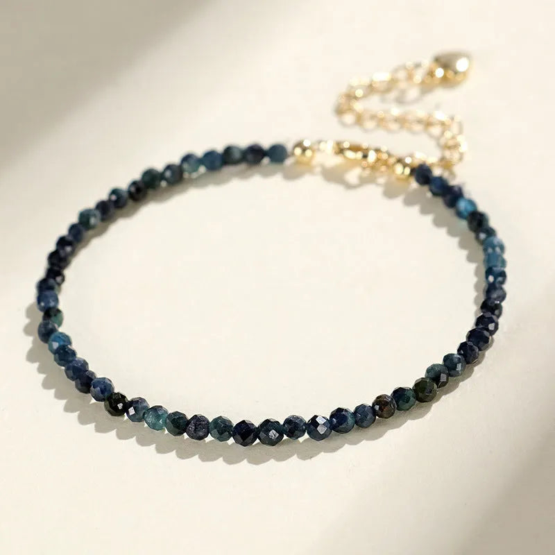 Close-up of a blue tourmaline beaded bracelet with metallic spacer beads on a woman's wrist.