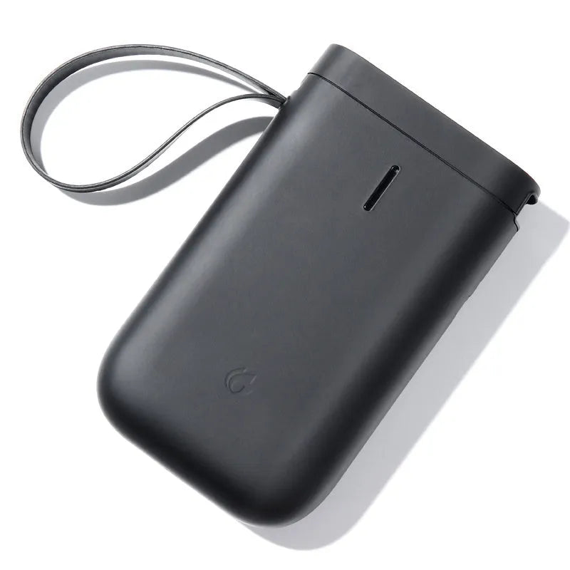 D11 compact white Bluetooth thermal label printer with USB cable and roll of label paper on a desk.