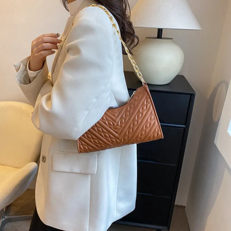 Brown pleated PU leather baguette bag with a gold-tone chain shoulder strap and a soft top handle.