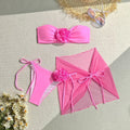 Pink women's swimsuit set with tied floral top, high-waisted bottoms, and matching skirt.