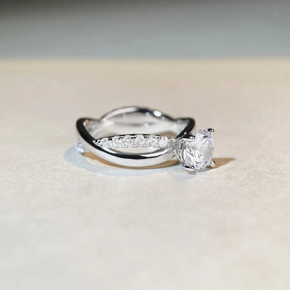 Silver geometric cross ring with a 1 carat moissanite in a four-claw twisted arm setting.