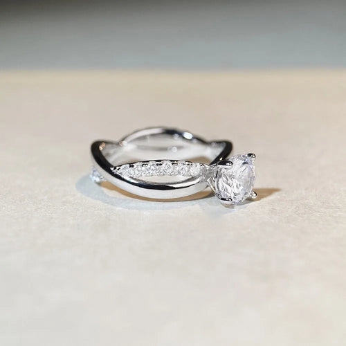 Silver geometric cross ring with a 1 carat moissanite in a four-claw twisted arm setting.