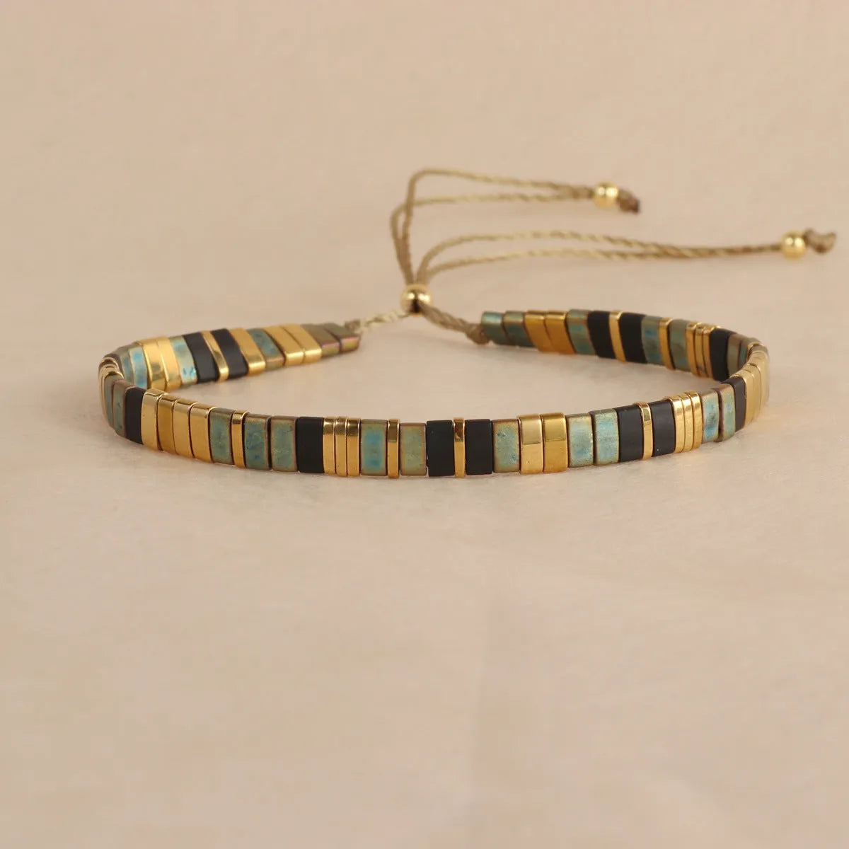 Geometric glass and coloured glaze beaded bracelet in milky white on a wrist.