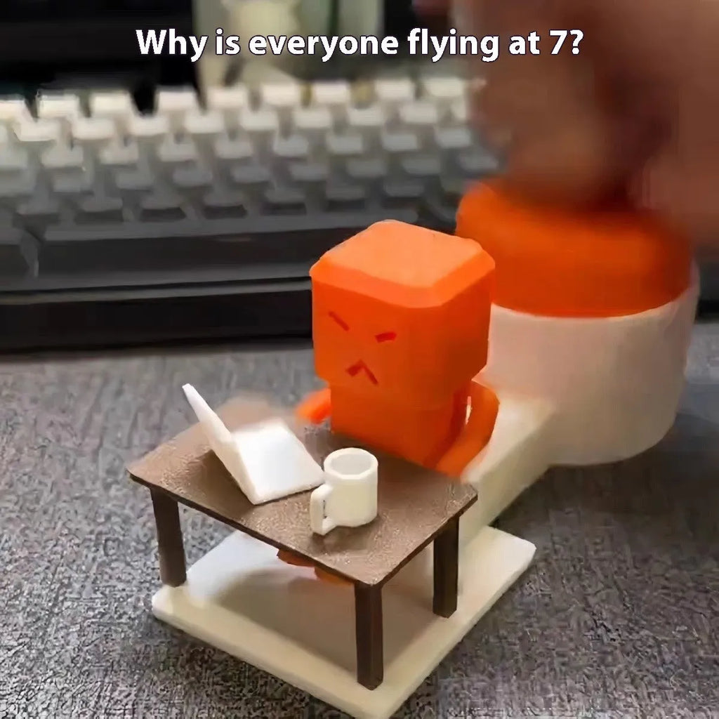 Orange plastic table-turning decompression toy on a desk.