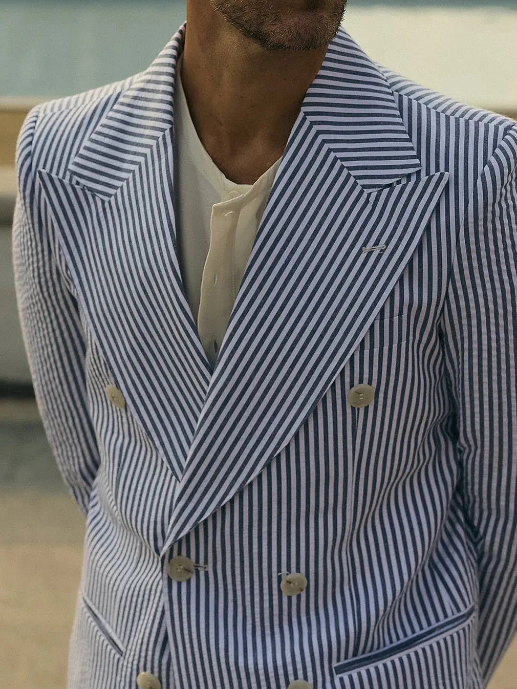 Blue and white striped polyester suit set with blazer and trousers on a hanger.