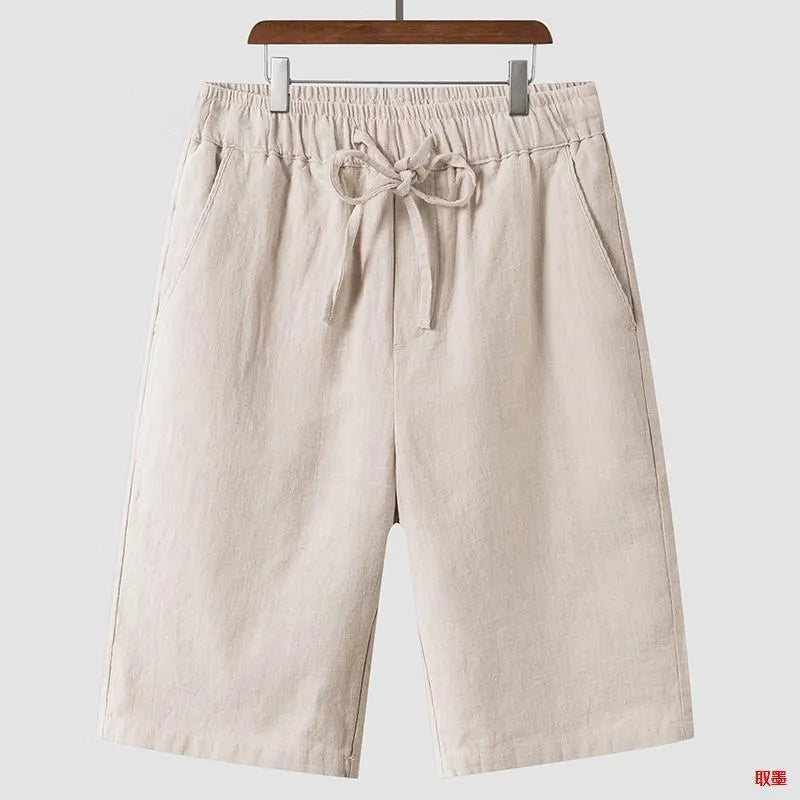 A pair of beige linen shorts for men with a loose, cropped fit and a mid-rise elasticated waistband.
