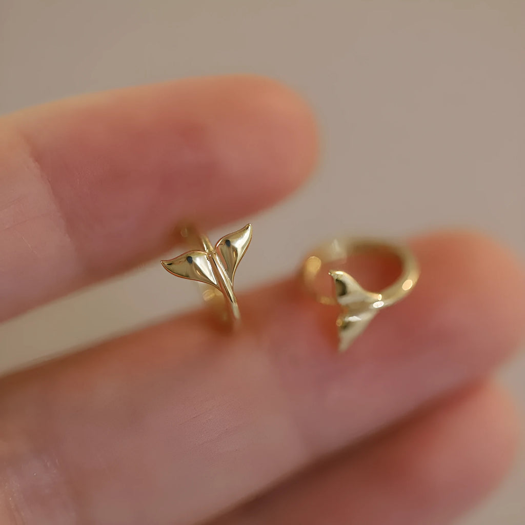 S925 sterling silver fishtail hoop earrings in gold colour on a white background.
