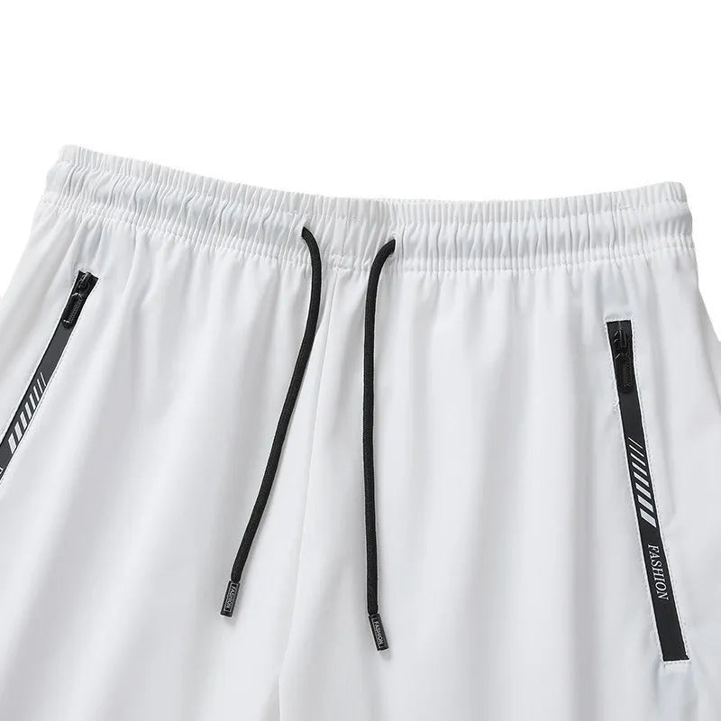 Man wearing loose fit black nylon sports shorts with an elastic waistband.