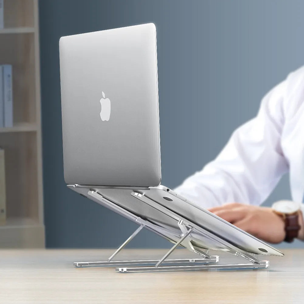 Aluminium laptop stand in silver, folded flat next to an open laptop showing its adjustable height mechanism.