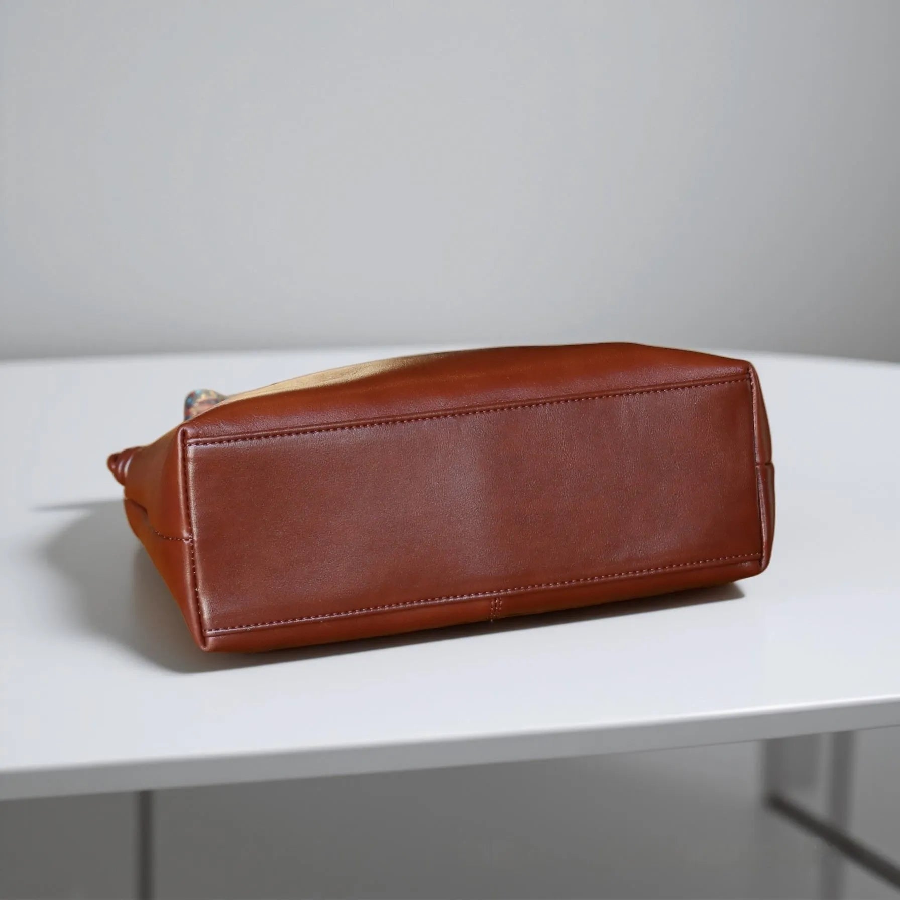 Genuine leather creative large capacity hand and shoulder commuter bag in caramel colour with pillow shape and patchwork details