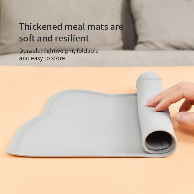 Blue silicone pet feeding mat with cat head shape under food and water bowls.