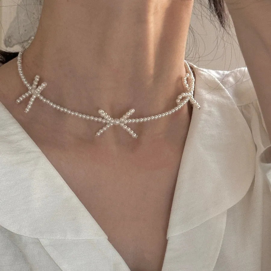 White imitation pearl necklace with a central bow pendant on a chain, adjustable from 31cm to 40cm.