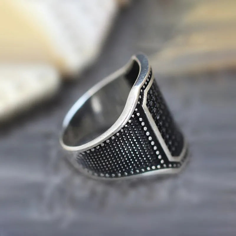 Black alloy ring with copper inlay surrounding a central zircon stone.
