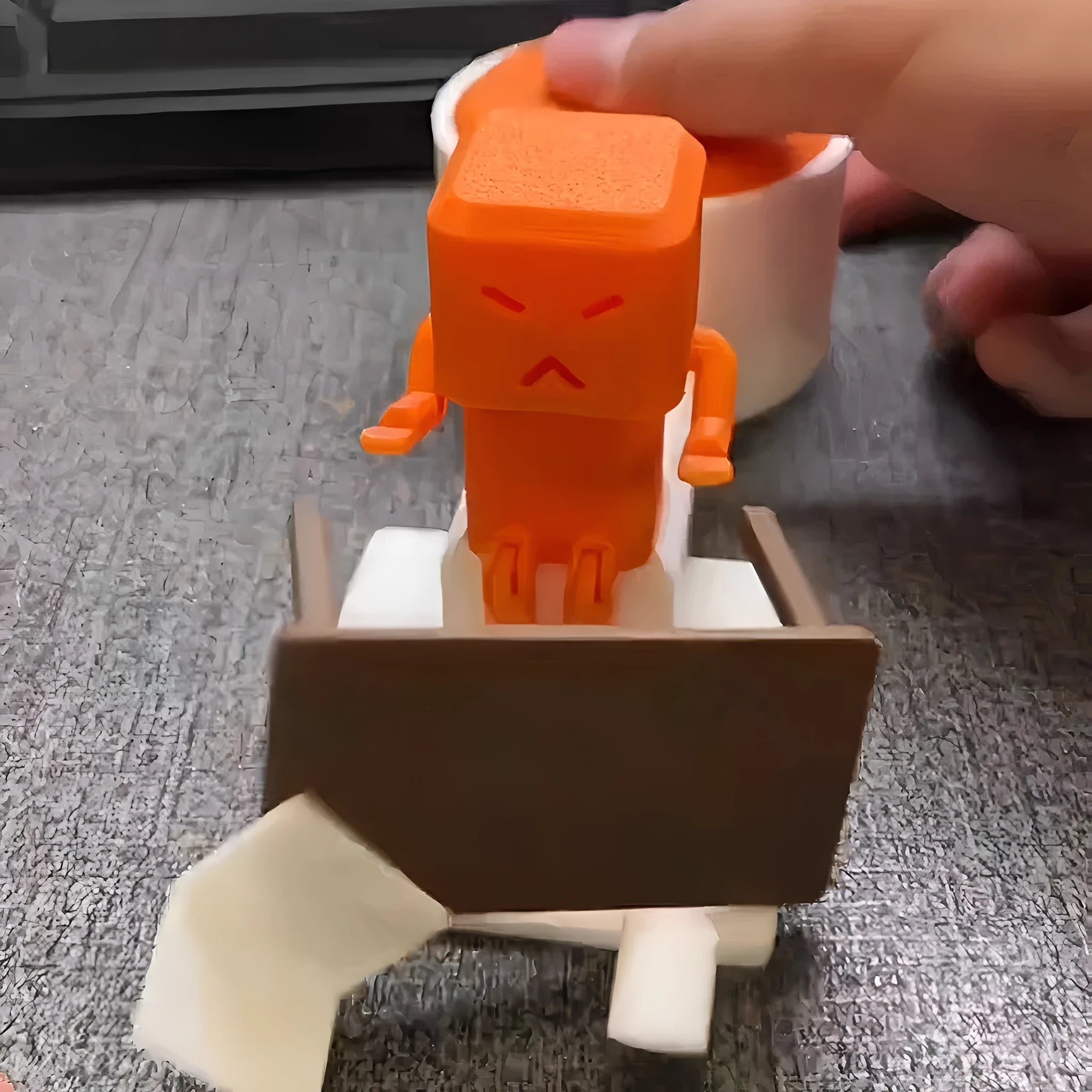 Orange plastic table-turning decompression toy on a desk.