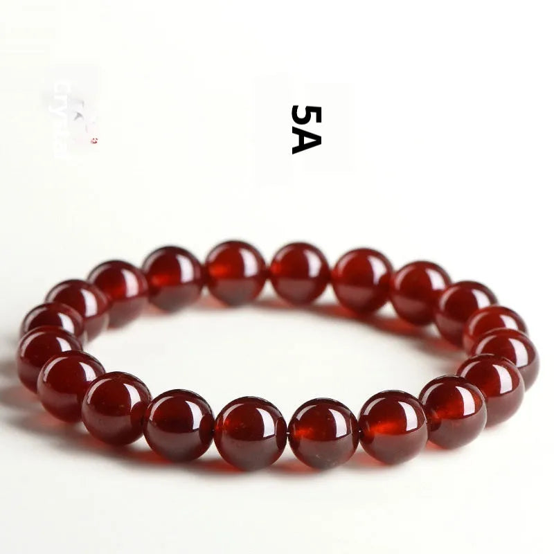 Natural orange red garnet ball bead bracelet with ruyi charms on a wrist.