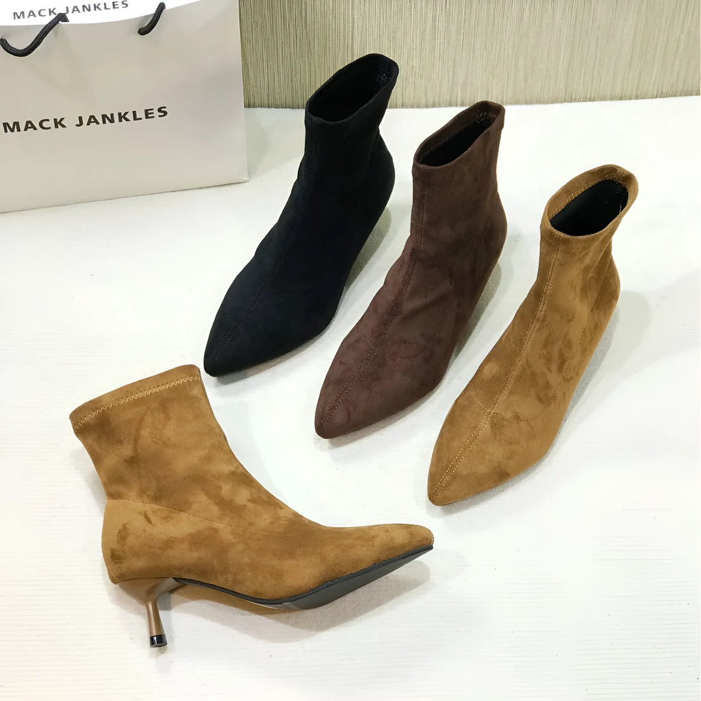 Women's black pointed toe ankle boots with stiletto heel on a plain background
