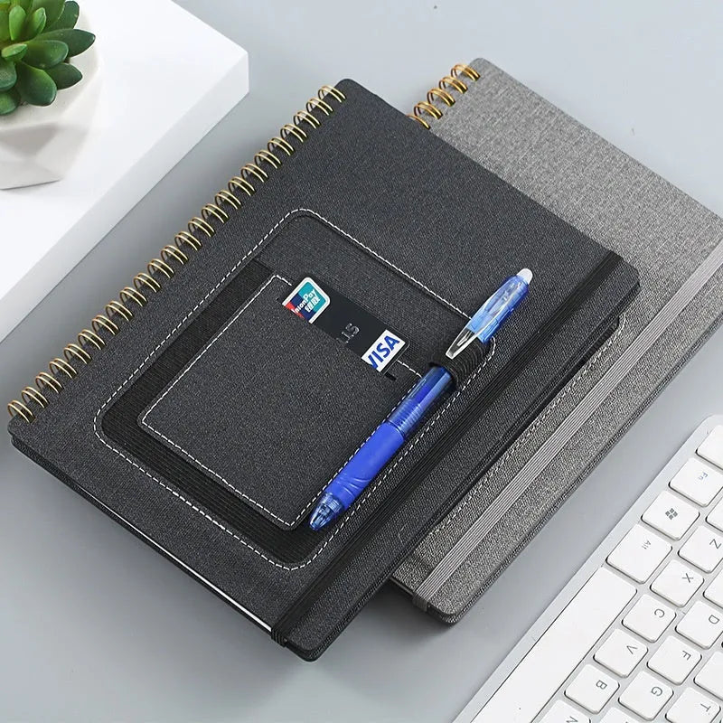 Erasable coil notebook with stone paper, showing a black cover option and a pen on a wooden desk.