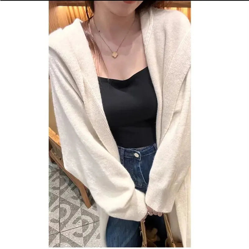 Women's long hooded knitted cardigan in oatmeal colour, showing below-knee length and loose fit.