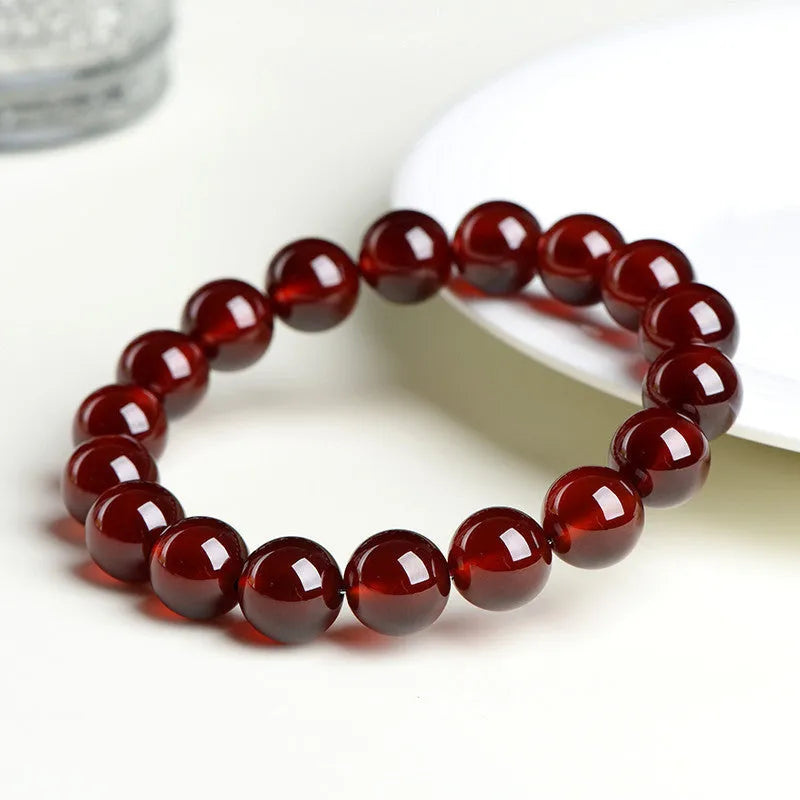 Natural orange red garnet ball bead bracelet with ruyi charms on a wrist.