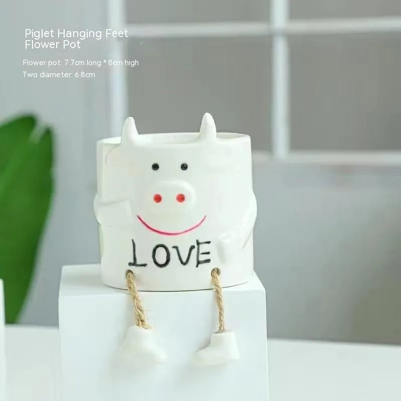 Ceramic cartoon-style hanging foot flowerpot for succulent plants on a desktop.