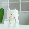 Ceramic cartoon-style hanging foot flowerpot for succulent plants on a desktop.