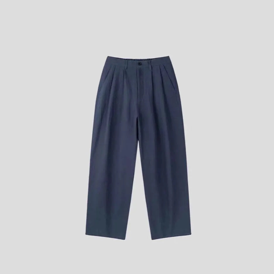 Men's apricot coloured loose-fit cotton linen blend trousers on a hanger, showing zip fly and mid-waist design.