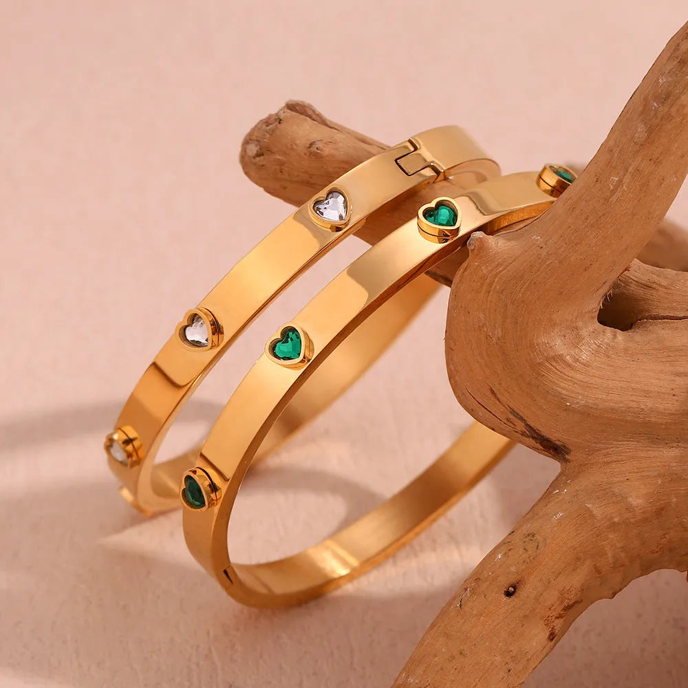 A stainless steel bracelet with a small micro-inlaid peach heart charm, shown in a golden electroplated finish.