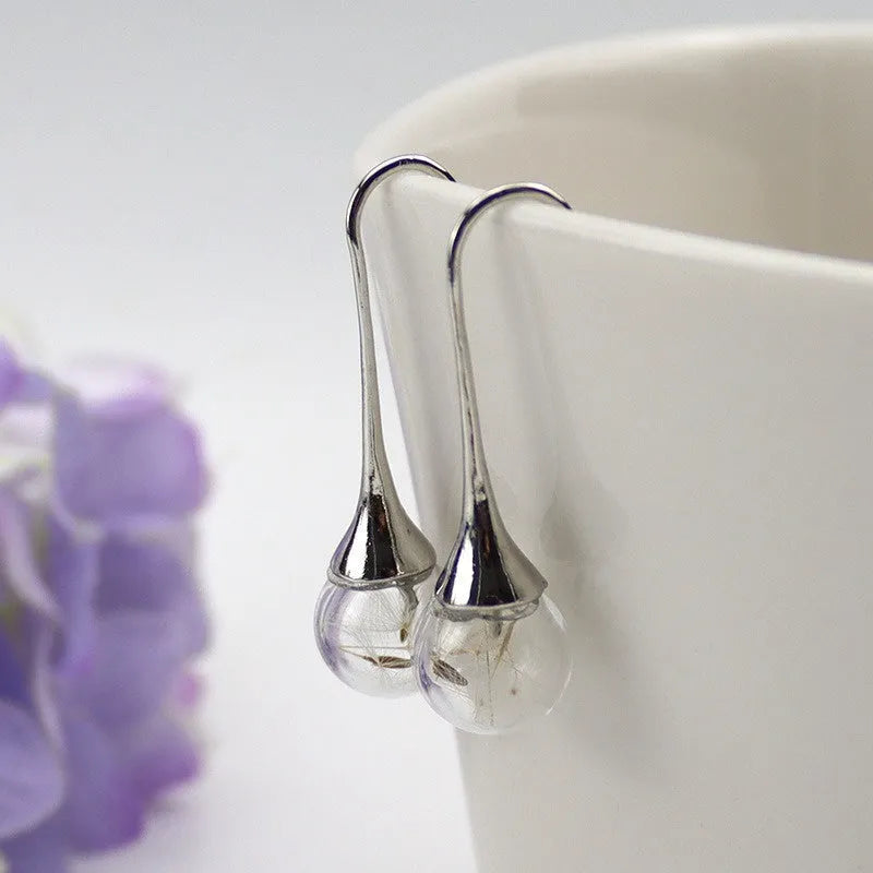 Transparent glass ball earrings with dandelion seed design inside, shown with French hooks