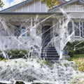 White cotton Halloween spider web decoration with plastic spiders on dark background