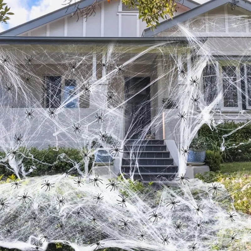 White cotton Halloween spider web decoration with plastic spiders on dark background