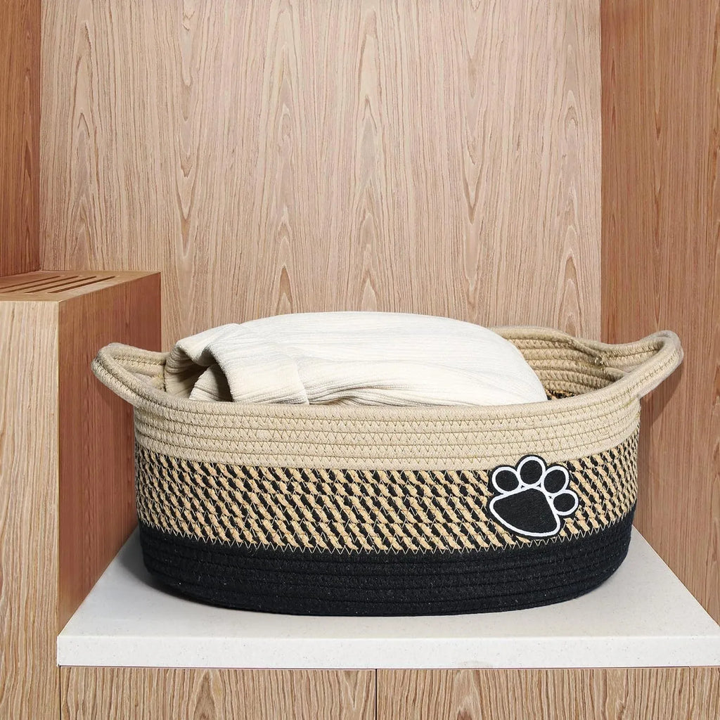Light beige handmade woven cotton rope storage basket with wood accents and a handle.