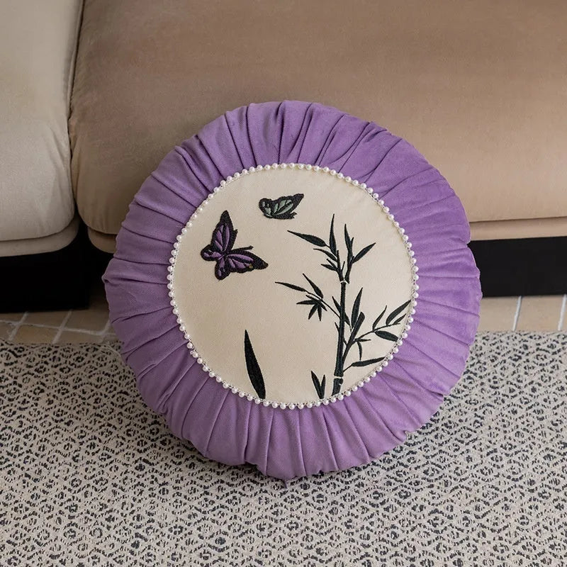Square beige couch pillow with detailed Chinese-style butterfly embroidery.