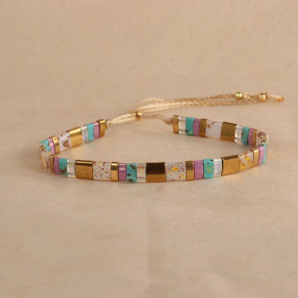 Geometric glass and coloured glaze beaded bracelet in milky white on a wrist.