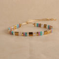 Geometric glass and coloured glaze beaded bracelet in milky white on a wrist.