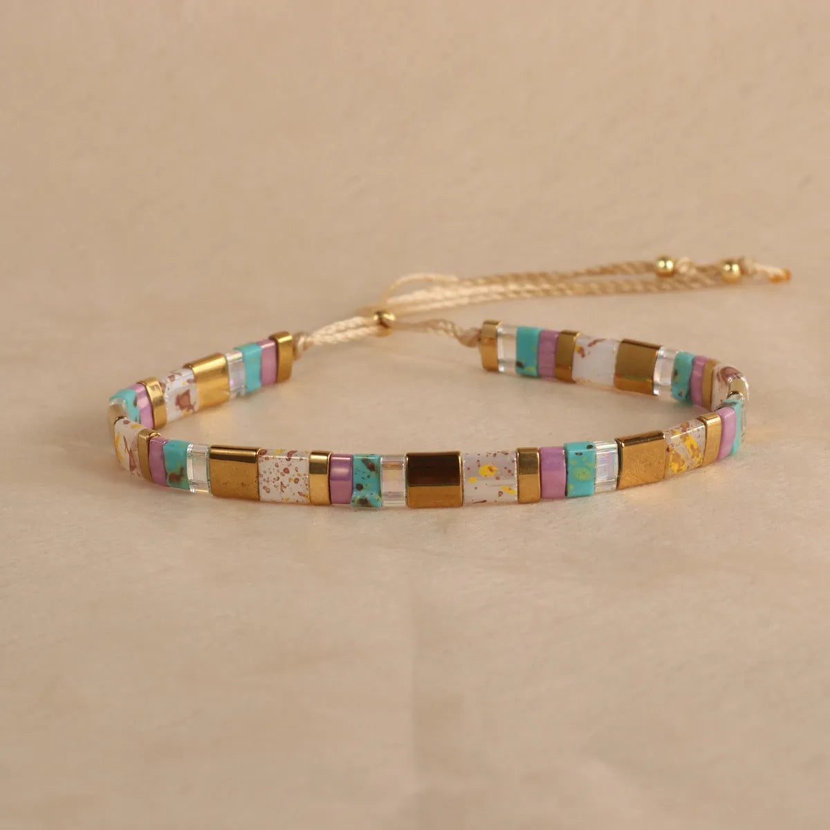 Geometric glass and coloured glaze beaded bracelet in milky white on a wrist.