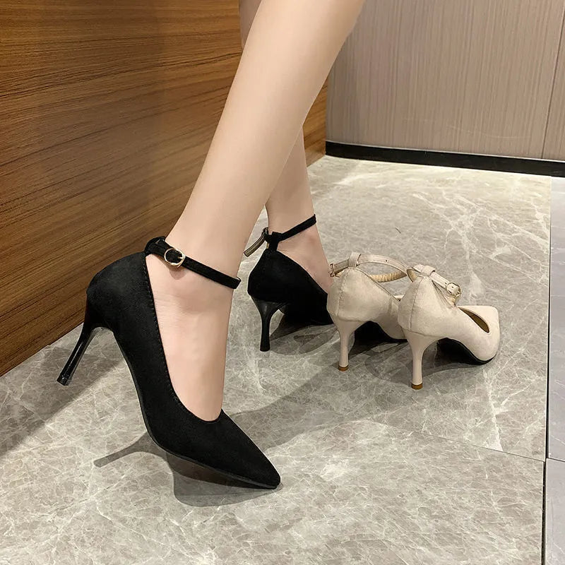 Women's black stiletto heel pump shoes with a buckle and skull pattern lining on a white background.