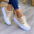 Women's white lace-up flats sneakers with rivet decoration on the side, showing round toe and casual style.