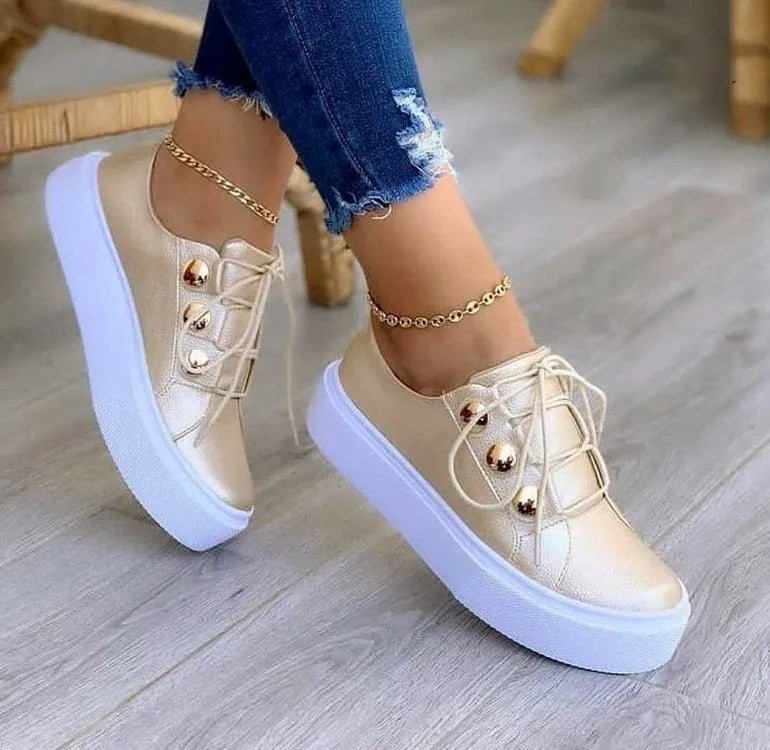 Women's white lace-up flats sneakers with rivet decoration on the side, showing round toe and casual style.