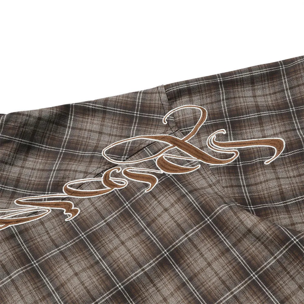 Man wearing a brown plaid short sleeve shirt with embroidery on the lapel